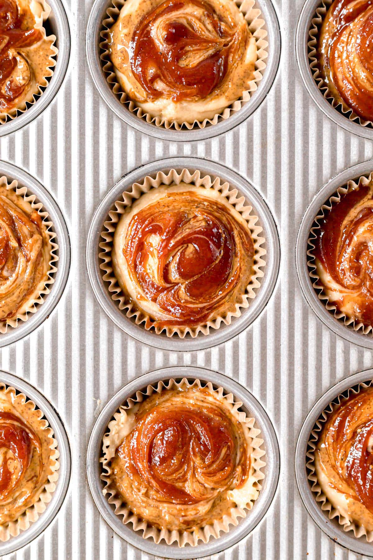 almond butter and guava jelly swirled on top of muffins in muffin pan before baking