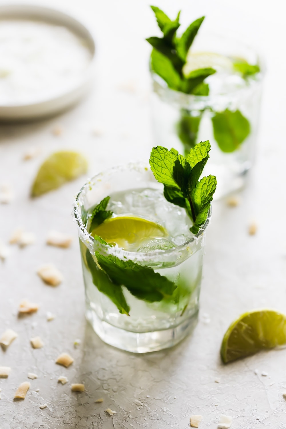 two glasses of coconut mojito drink with mint leaves and lime wedges