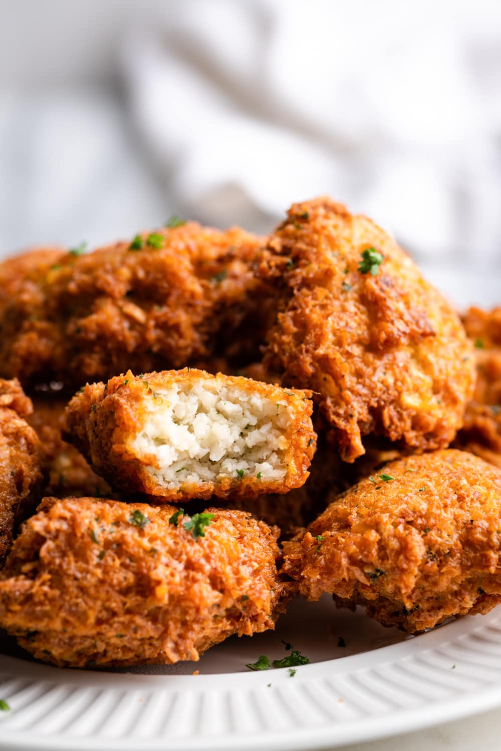 frituras de malanga on a white plate with one of the fritters showing the soft, tender inside