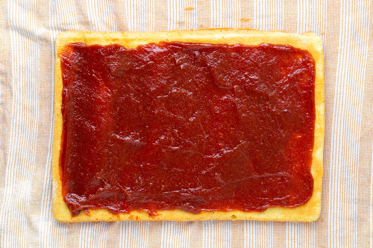 Brazo gitano laying on a damp towel that is topped with a guava filling before being rolled up