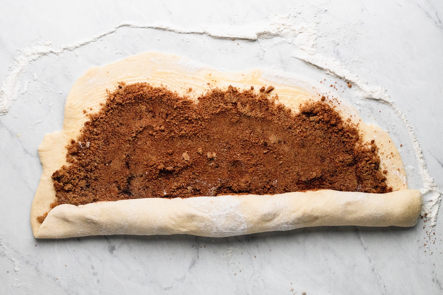 rolling the dough with cinnamon sugar for cinnamon rolls