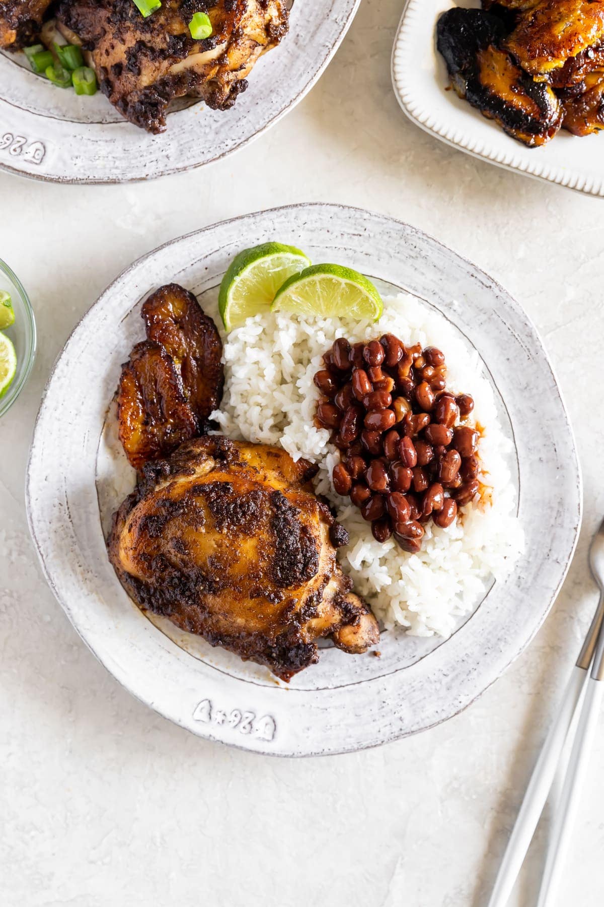 jerk chicken on a white plate with rice, beans, and sweet plantains