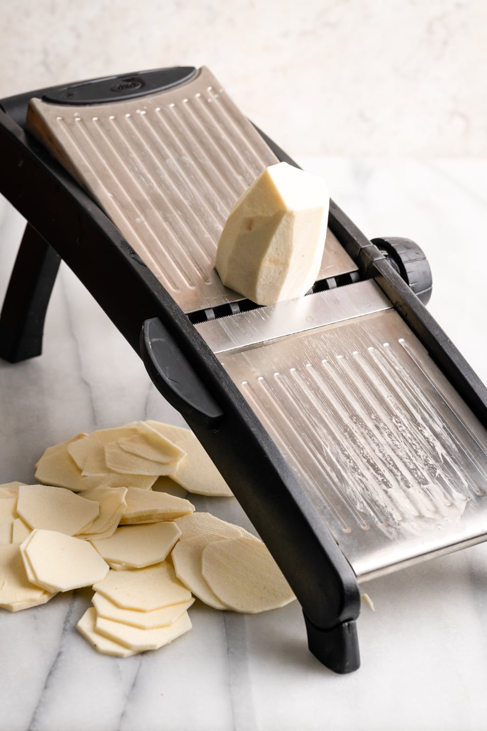 peeled malanga being sliced on a mandoline