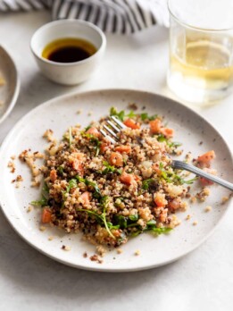 Salmon served with quinoa, tomatoes, onions, and arugula