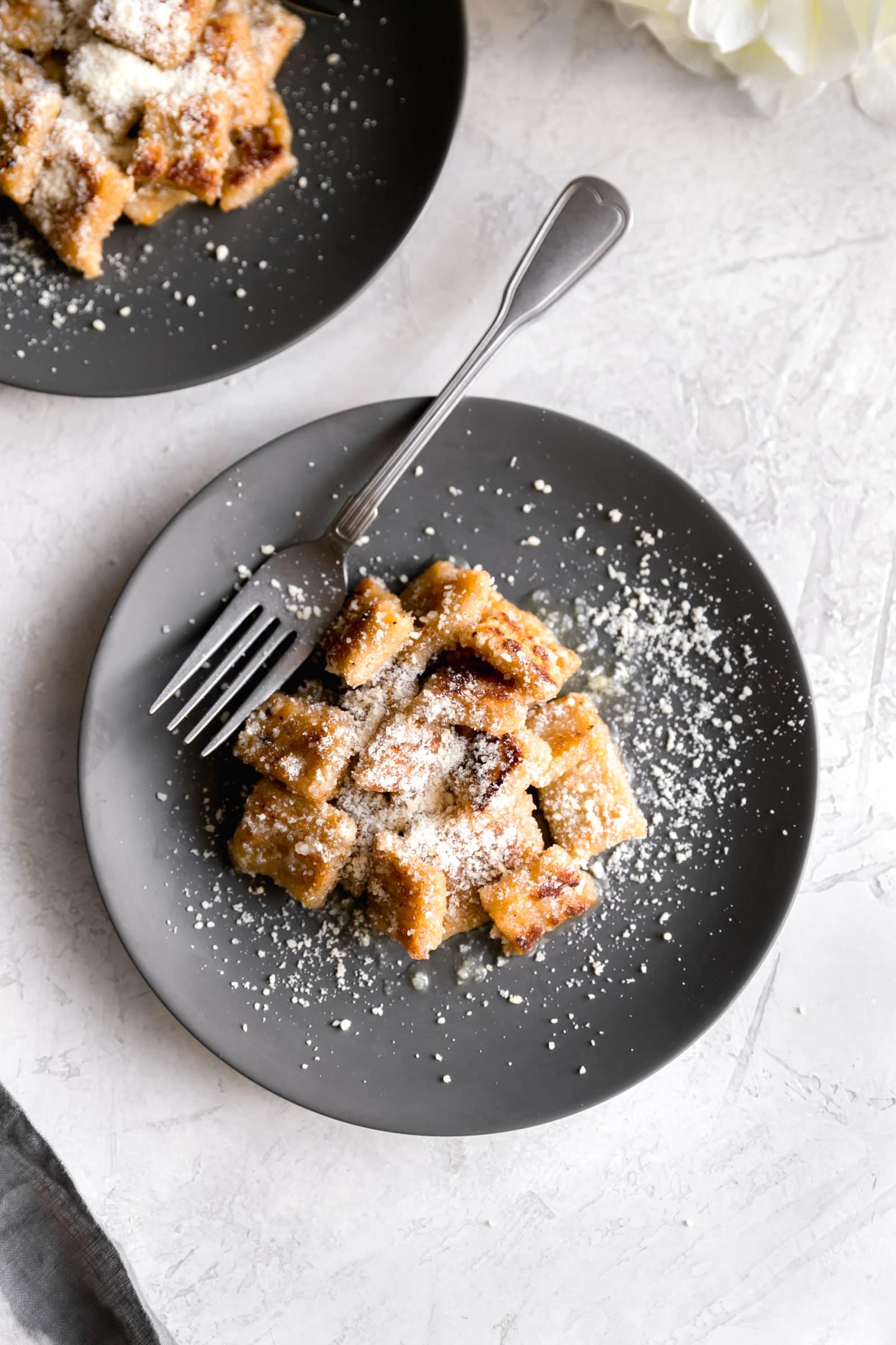 sweet plantain gnocchi on a gray plate sprinkled with parm cheese and tossed in brown butter garlic sauce